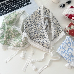 Lace-trimmed floral triangle headscarf in green and beige cotton displayed on a desk