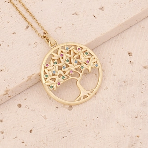 Macro shot of gold Tree of Life pendant with multicolor cubic zirconia on stone texture