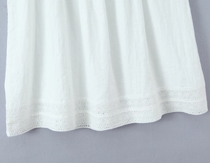 Detailaufnahme des weißen Kleidssaums mit aufwendiger hohler Spitzenstickerei und Webstruktur