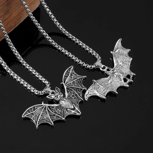 Close-up of two punk-style silver bat pendants with skeletal details on box chain