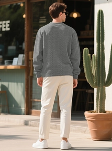 Outdoor shot showing the back of a grey knit sweater with detailed jacquard texture and fit