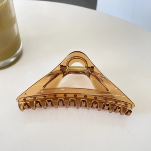 Macro shot of 12cm translucent amber triangular hair claw clip with golden metal spring