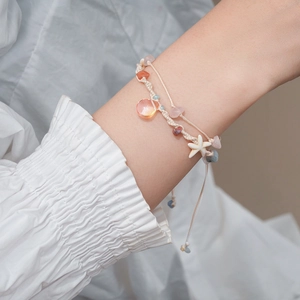 Detail of beaded shell bracelet with starfish and teardrop pendant on wrist