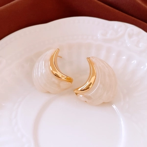 Detail of crescent moon earrings in off-white finish with gold-plated metal borders