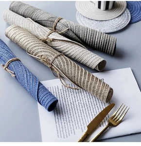 Macro detail of rolled woven placemats in blue and grey showing braided texture and rope ties