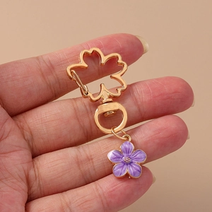 Pastel purple daisy flower keychain with golden cherry blossom clasp on beige background