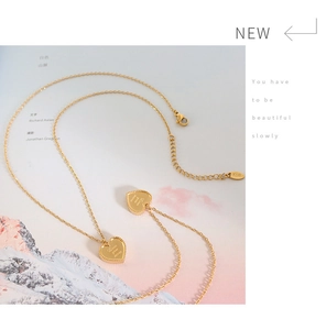 Gros plan du pendentif cœur en or 18 carats avec gravure Love you more sur fond de magazine