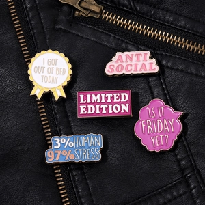 Detail von fünf bunten Emaille-Pins mit Slogans auf einer schwarzen Lederjacke