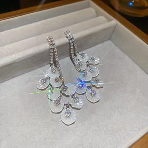 Détail de boucles d'oreilles longues à pampilles avec cristaux et pétales blancs superposés