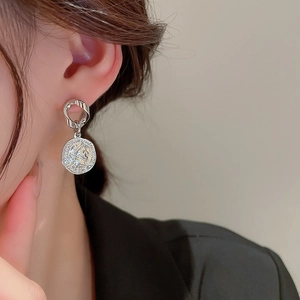 Close-up of silver asymmetrical chain pearl earrings with coin portrait on a model