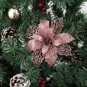 Fleur de poinsettia rose pailletée avec pétales ajourés sur un sapin de Noël