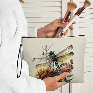 Dragonfly canvas cosmetic bag with floral print and zipper closure held by a hand