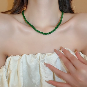 Gros plan d'un collier de perles de verre géométriques vert émeraude sur un mannequin