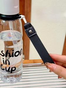 Detail of round cup rim and nylon strap with leather fixings on a clear plastic bottle