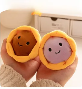 Gros plan de mini breloques de tartelette en peluche dans les mains montrant une texture douce