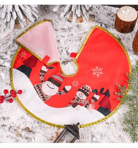 Detail of red Christmas tree skirt with snowman print and gold trim on snow background