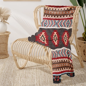 Soft flannel blanket with ethnic geometric patterns draped over a stylish rattan chair