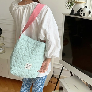 Detail of heart-quilted texture on green canvas bag with pink shoulder strap