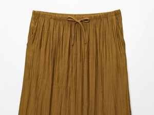 Detail of ochre yellow textured midi skirt with elastic drawstring waist and side pockets