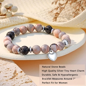 Detail of beaded natural stone bracelet with a silver heart charm on a stone tray