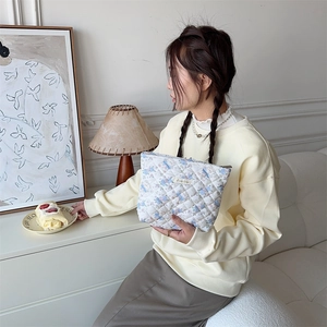 Detailed shot of white quilted cosmetic bag with blue floral and bear prints