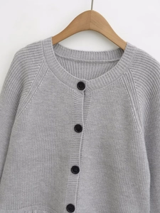 Close-up of grey knit cardigan with round neck, ribbed texture, and black buttons