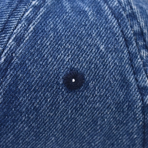 Dettaglio del tessuto denim blu navy con ricamo rifinito su un berretto da baseball