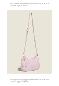 Detail of pink crescent bag featuring embossed butterflies and a silver butterfly charm