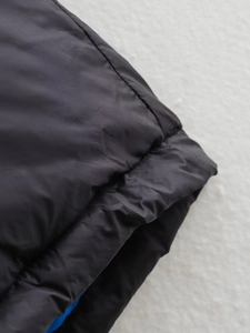 Détail du gilet matelassé noir avec doublure bleue et coutures de précision soignées