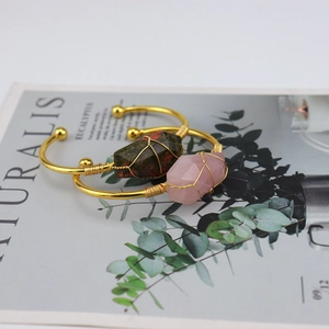 Detail of wire-wrapped gold bracelet featuring natural raw pink and green crystals