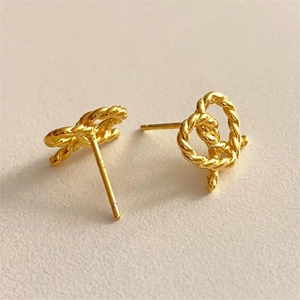Macro shot of gold intertwined C-shape stud earrings with a vintage twisted rope texture