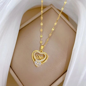Goldene Herzkette mit LOVE-Gravur und Zirkonia-Inlay auf weißem Seidenhintergrund