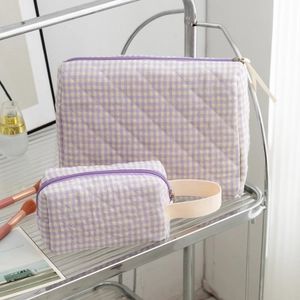 Detailed macro view of purple and yellow quilted cotton cosmetic bags on a glass shelf