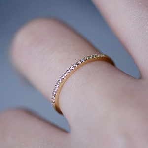 Vista macro di un anello sottile in argento dorato con scintillanti zirconi a pavé