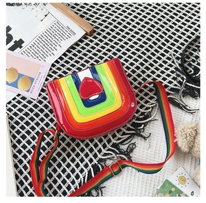 Detail of the colorful rainbow striped crossbody bag featuring a glossy red heart ornament