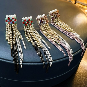 Detail von eleganten Perlenohrringen mit bunten Kristallfransen auf blauer Lederbox