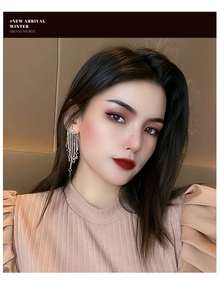 Close-up of star tassel earrings featuring long metal chains on a model profile