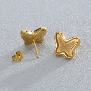 Chic golden butterfly stud earrings with stainless steel pins on a grey textured surface