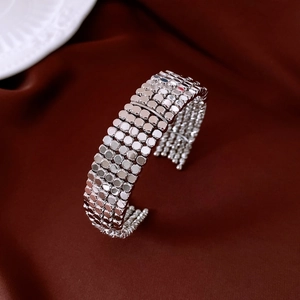 Close-up of multi-row silver sequin cuff bracelet on textured burgundy velvet background