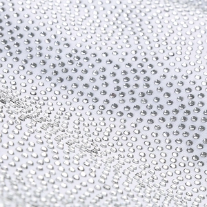 Dettaglio di strass argentati scintillanti sul tessuto bianco di un abito elegante