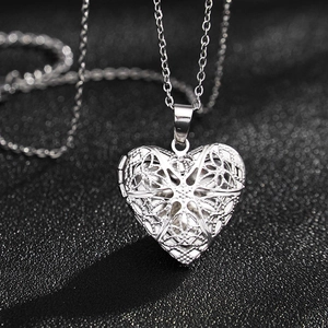 Vista macro de colgante guardapelo de plata con forma de corazón y diseño calado fino