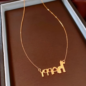 Macro detail of 24K gold plated necklace with HAPPY letter and animal pendant on velvet