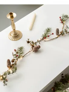Macro shot of warm LED lights with pine cones, red berries and bells on pine garland