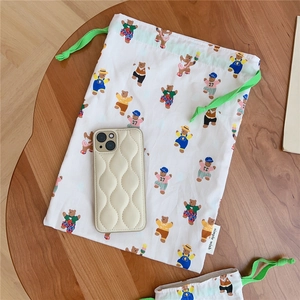 Detail of drawstring cotton pouch with bear prints and quilted beige phone case on wood