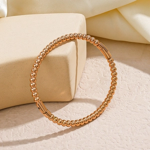 Elegant rose gold beaded bangle bracelet displayed on a premium stone jewelry stand