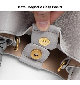 Detailed close-up of gray bucket bag featuring gold magnetic clasp and litchi grain leather