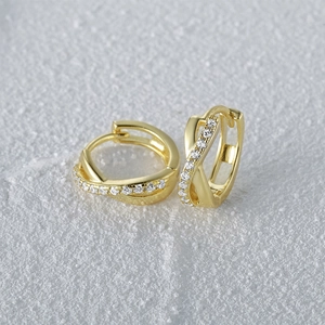 Detailed close-up of gold-plated silver crossover earrings with sparkling zircon stones