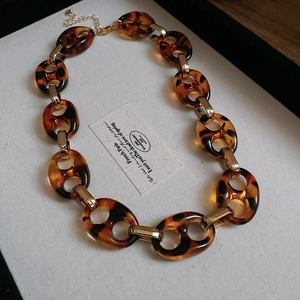 Dettaglio della collana a catena in resina leopardata con inserti dorati e anelli a forma di U