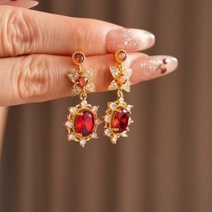 Makroaufnahme von Vintage-Blumenohrringen mit roten Oval-Edelsteinen und weißen Zirkonia