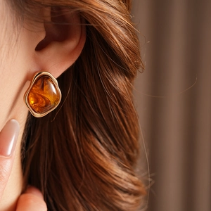 Close-up of vintage geometric earring featuring amber tortoiseshell resin and gold frame